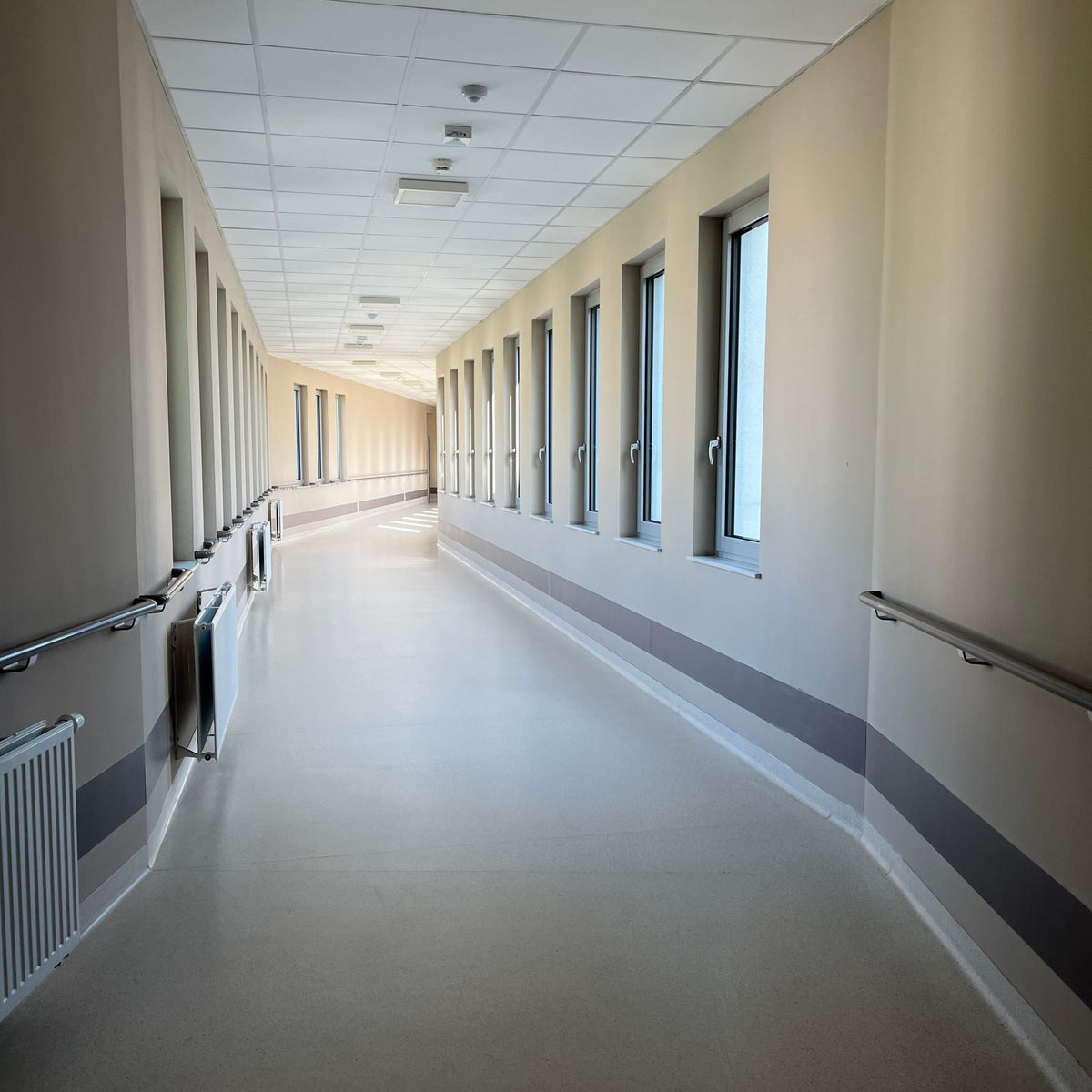 Bright, empty hospital corridor with large windows and handrails