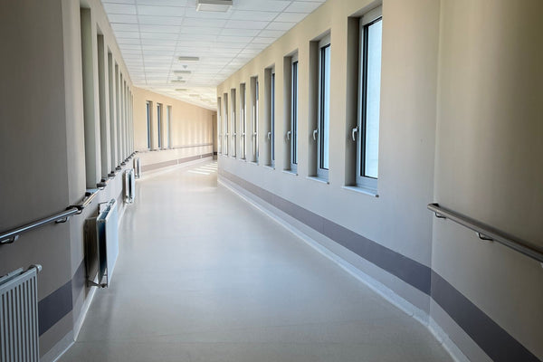Bright, empty hospital corridor with large windows and handrails