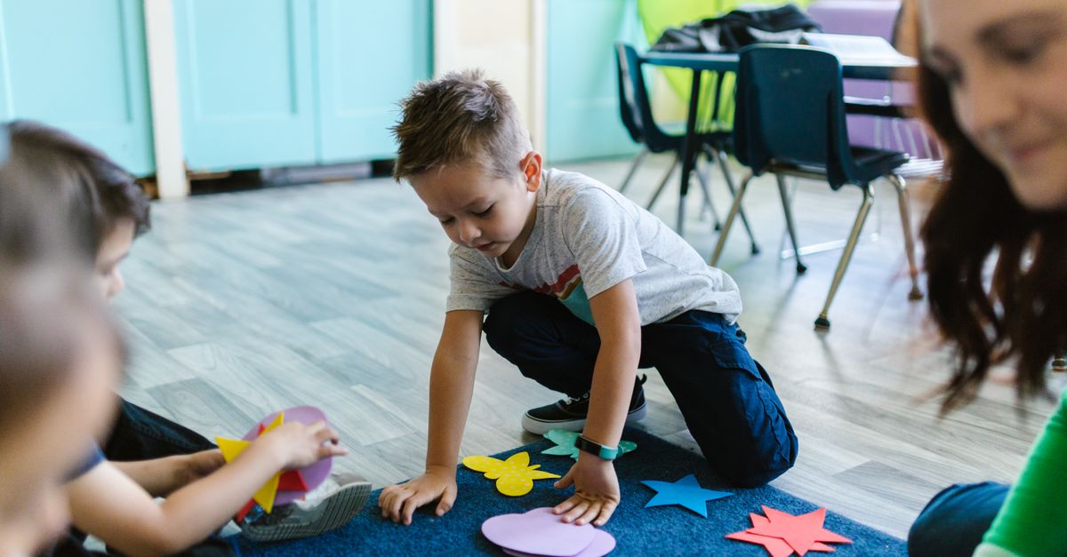Children playing with colorful shapes on a classroom floor