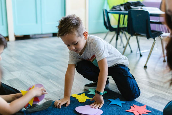 Children playing with colorful shapes on a classroom floor