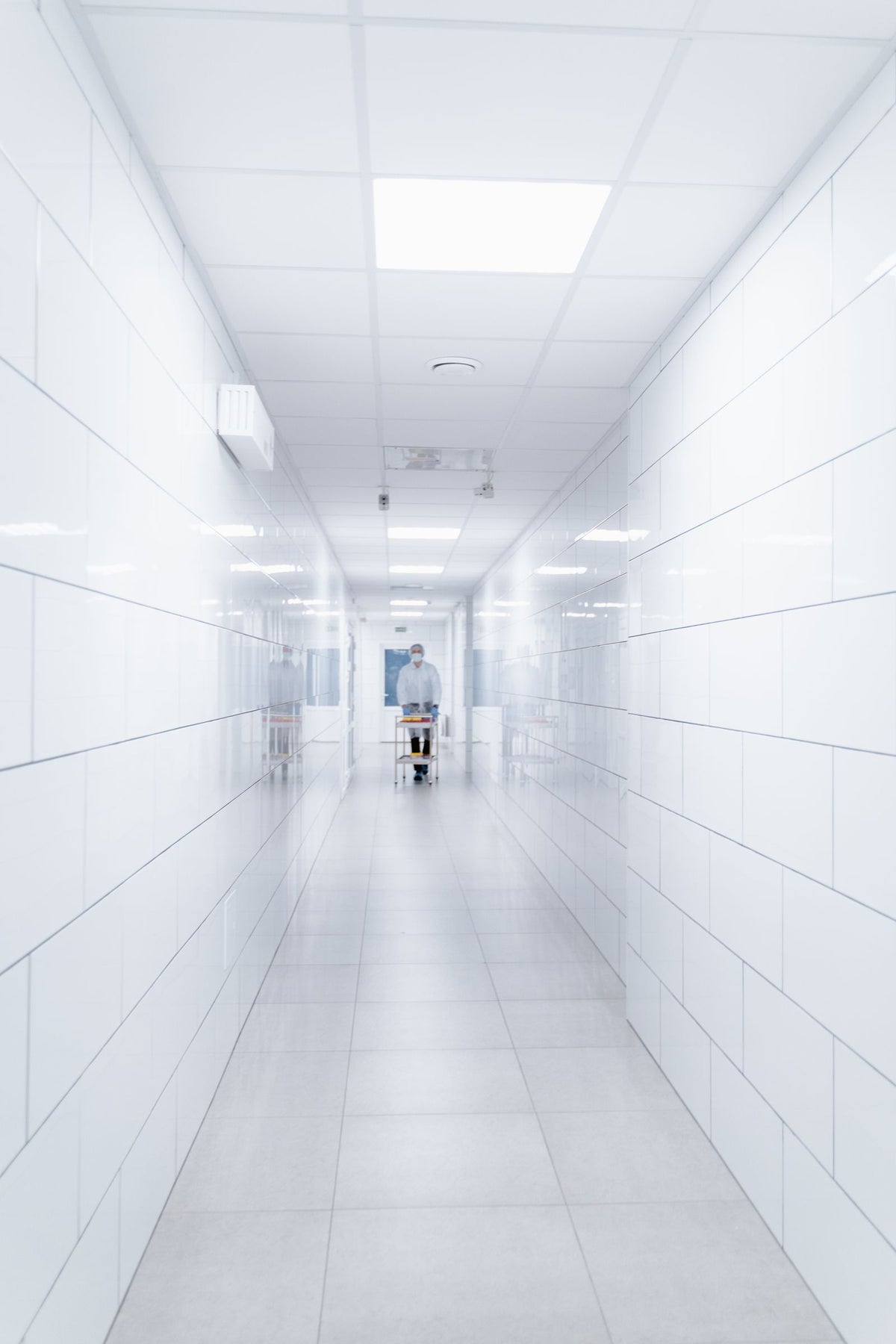 Clean hospital hallway with a healthcare worker walking in the distance