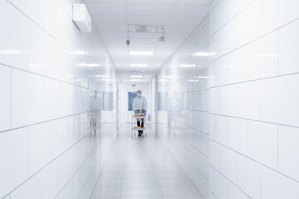 Clean hospital hallway with a healthcare worker walking in the distance