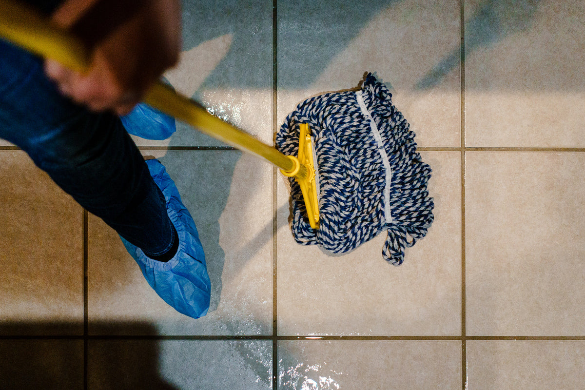 Mopping a wet tile floor while wearing non-slip shoe covers